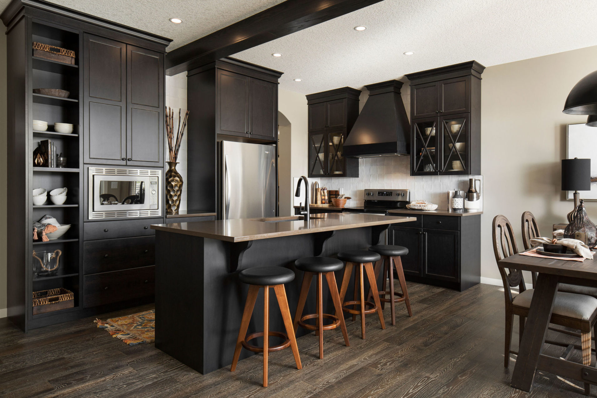 A kitchen with dark brown cabinets, wooden floors, and an island.