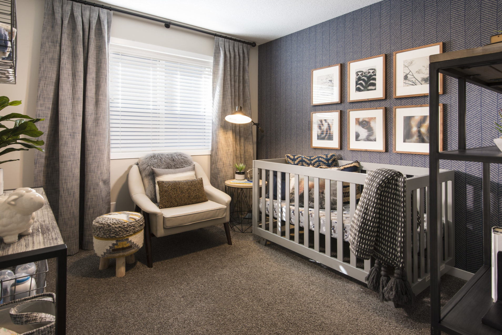 A carpeted bedroom with a crib, chair, shelving, and grey curtains.