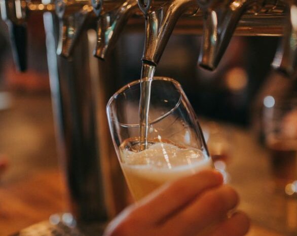 Beer is poured from a tap into a half-pint glass.