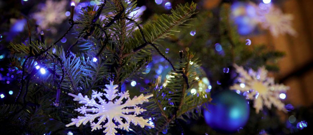 A white, plastic snowflake ornament in an illuminated Christmas tree.