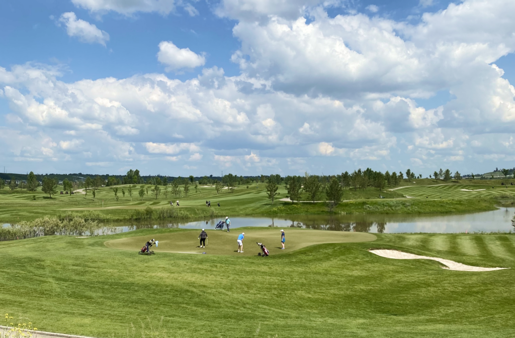 Golfers on course at Blue Devil Golf Club in South Calgary under blue skies