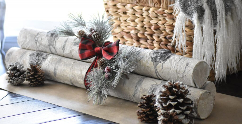 faux birch logs with boughs of pine tree and pine cones next to a fireplace