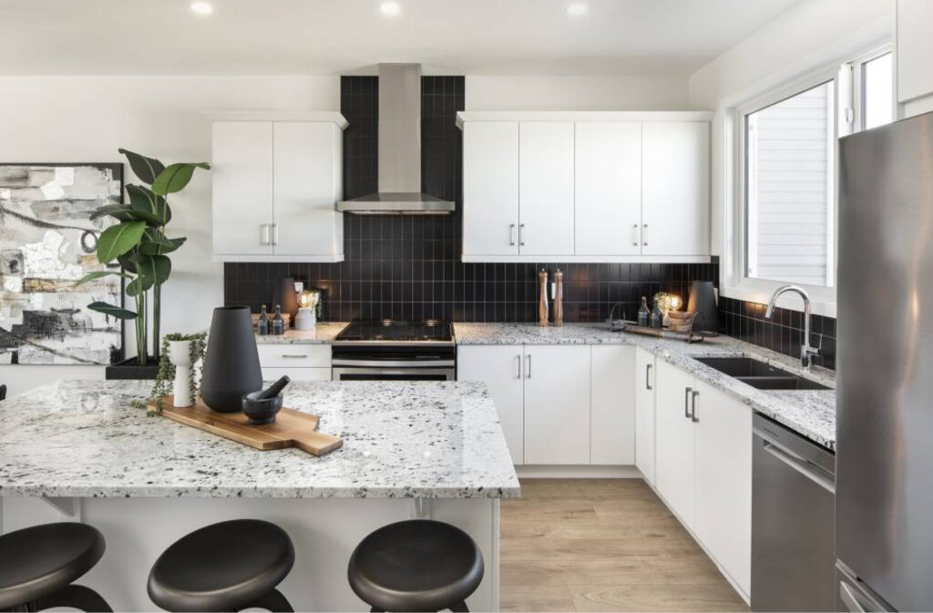 kitchen in a jayman built brooklyn home with white cabinets, marble countertops, and black accents