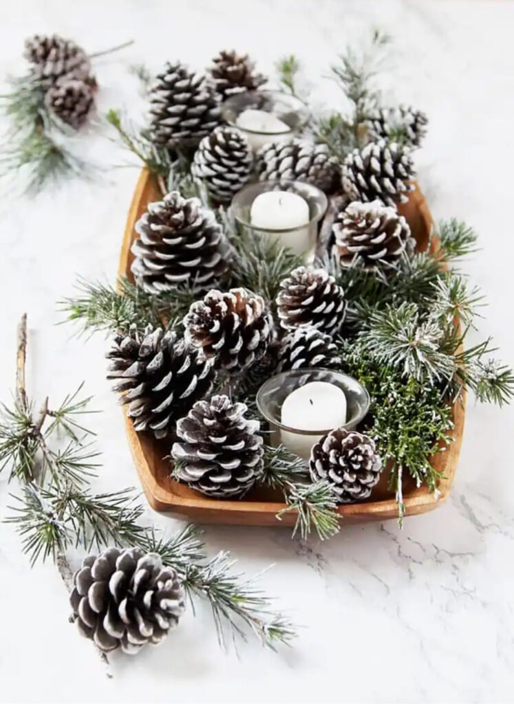centerpiece made of pinecones, pine tree boughs, and candles in votives