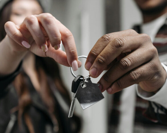 An interracial couple smiling and holding up a set of keys to their new home.