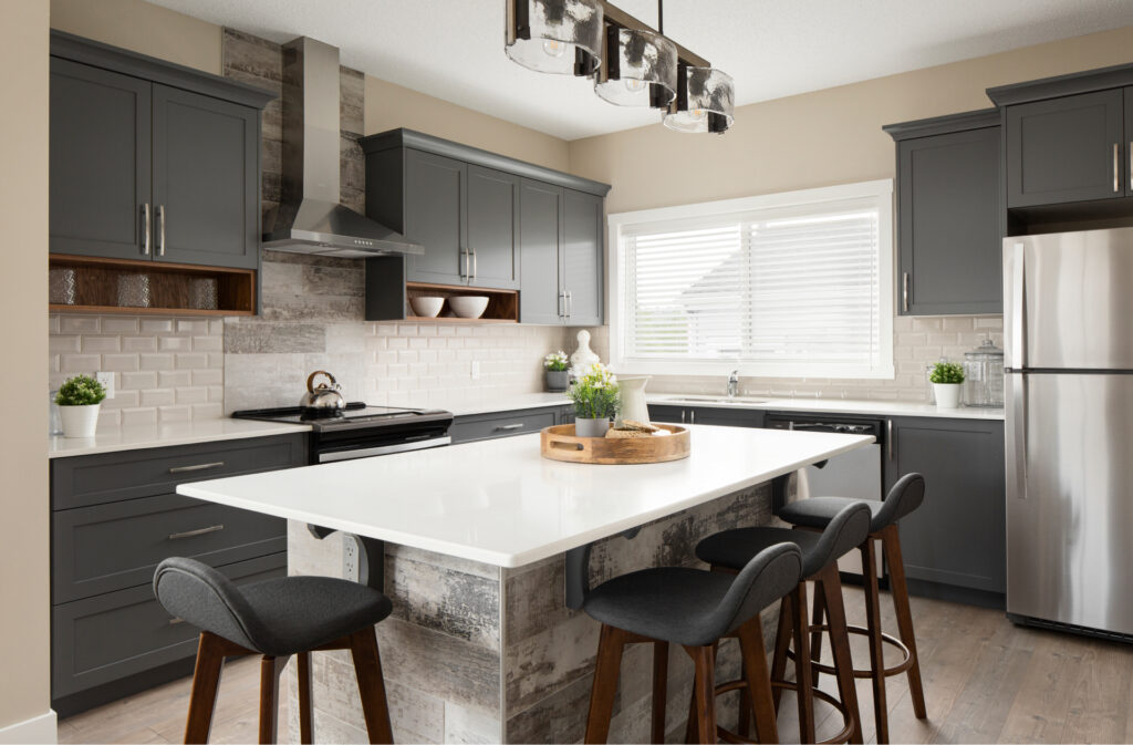 A kitchen in a Shane Homes Duplex, with dark grey cabinets and light white stone countertops.