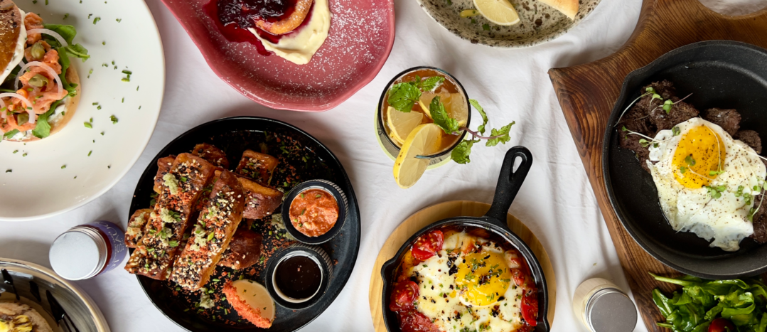 Variety of restaurant dishes on wooden table, representing South Calgary's diverse dining scene