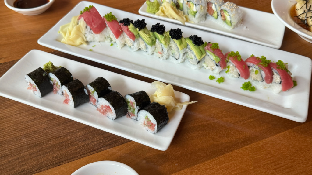 Sushi rolls on white dishes on a wood table, representing international cuisine and comfort food available in South Calgary