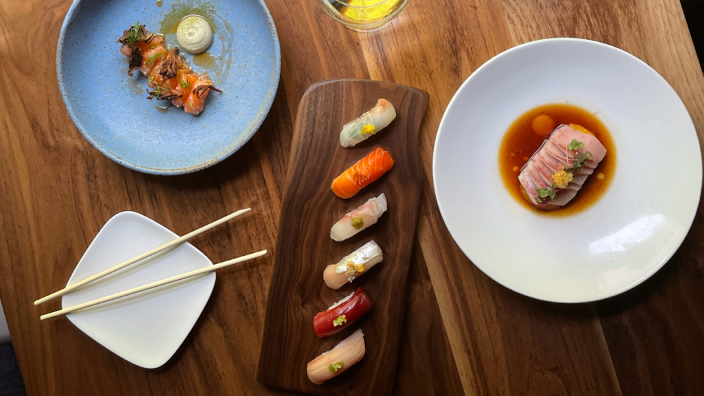 Overhead shot of fresh sashimi dishes on a wood table, representing Japanese cuisine in South Calgary